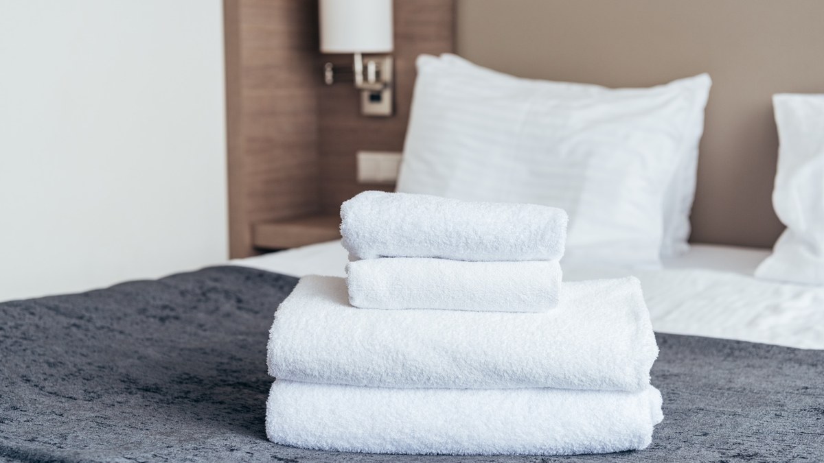 Toalhas dobradas sobre cama de hotel preparada para hóspedes