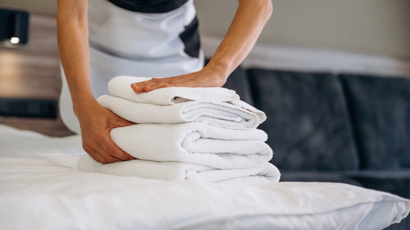 Toalhas limpas organizadas sobre cama em contexto de housekeeping hoteleiro