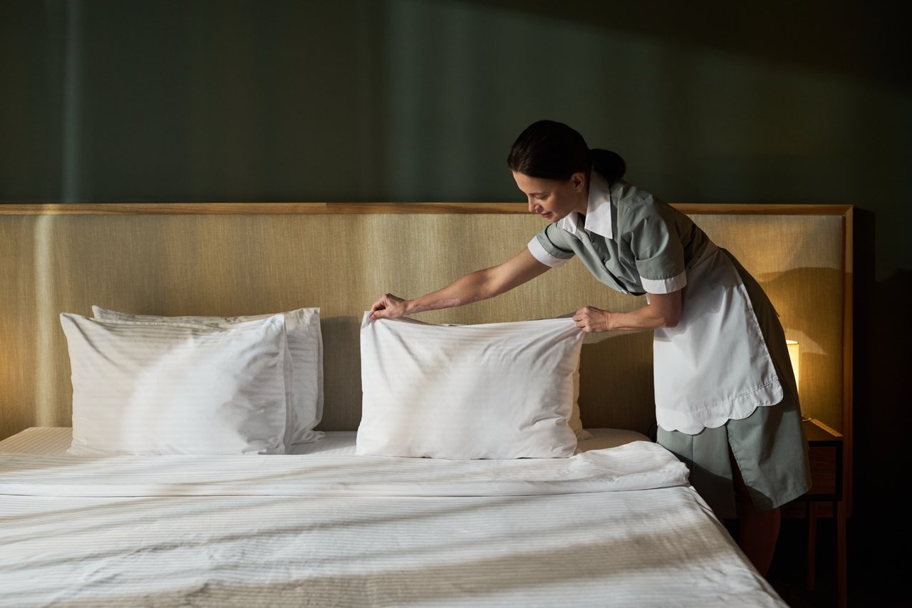 Equipa de limpeza hoteleira a preparar cama e reduzir retrabalho antes do check-in
